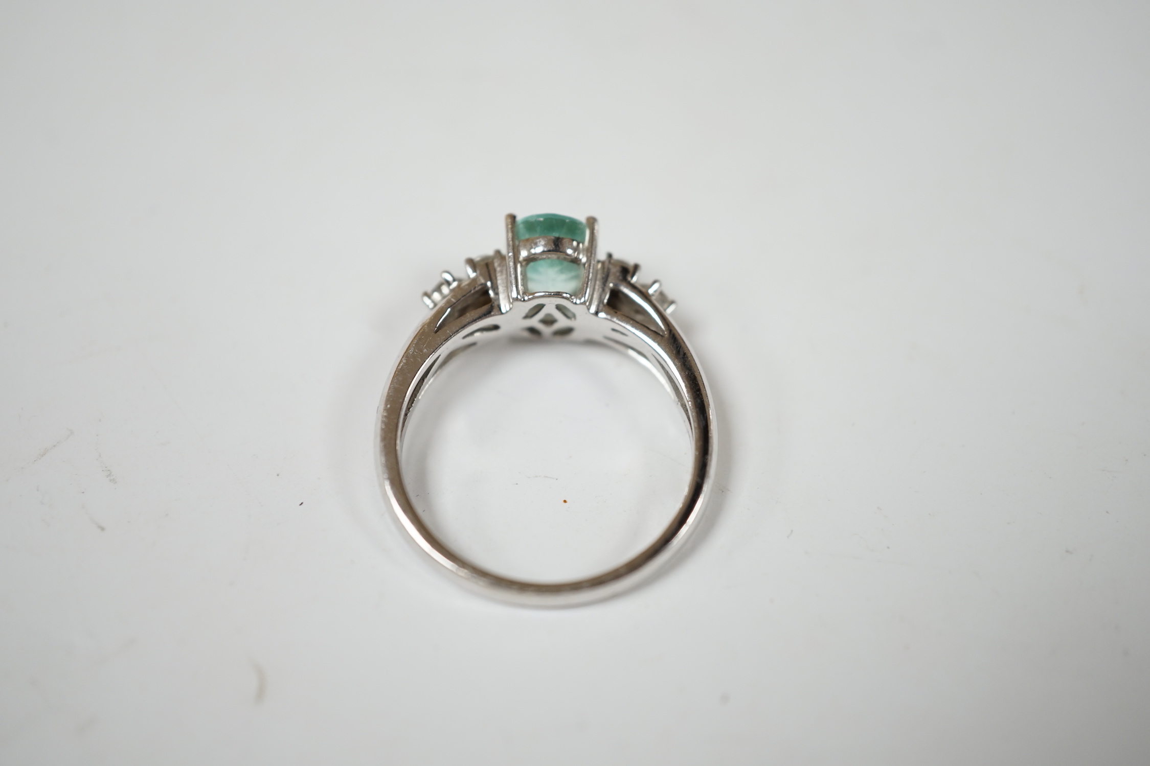 A modern 18ct gold and oval cut paraiba tourmaline set dress ring with six stone diamond set shoulders, size O, gross weight 4.9 grams.